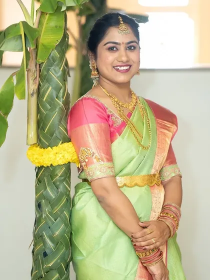 A happy bride is the most beautiful bride. Her fresh and radiant makeup complements her lovely light green and pink silk saree, perfect for a daytime wedding ceremony.