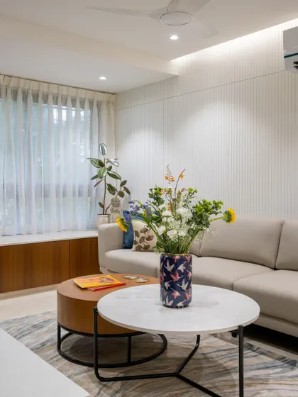 The living area uses a mix of textures, from the soft rug to the smooth marble coffee tables and the patterned vase, to create a space that is visually interesting yet calming.