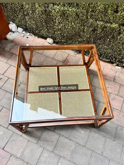A top-down view showing the glass surface and the woven cane shelf below.