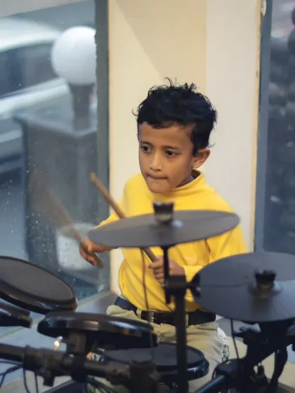 A young drummer keeping time with focus and determination. We believe in nurturing talent from the earliest age.