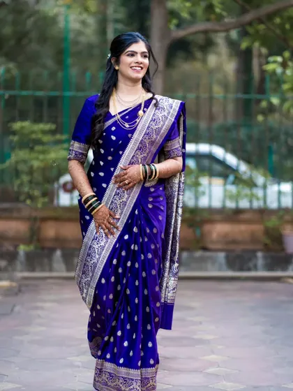 A full-length portrait of the bride in her blue Paithani, showcasing the complete look with her hair and mehndi.