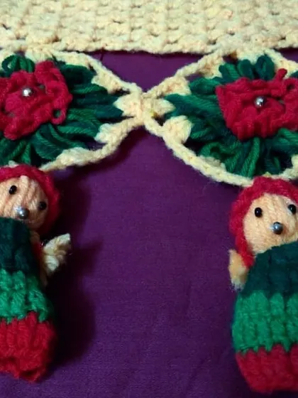 A close-up of a traditional crochet toran featuring floral motifs and adorable little dolls, showcasing intricate detail work.