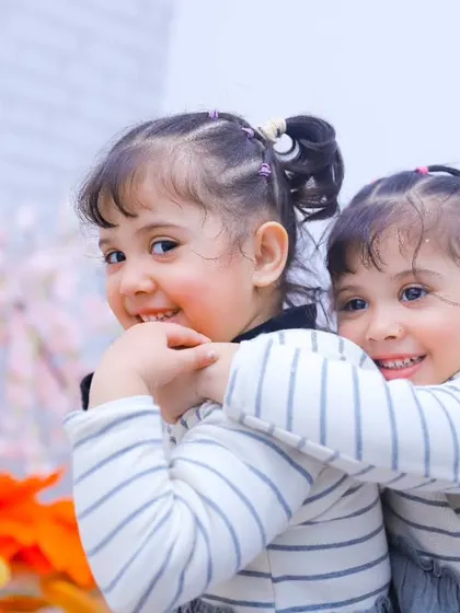 A big hug from behind! This shot captures the playful and affectionate bond between the twin sisters.
