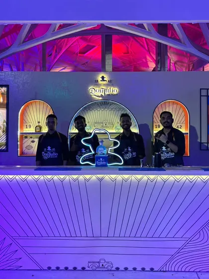 Our professional team posing behind the stylish, custom-built Don Julio bar. Their sharp uniforms and confident presence ensure that the service is as high-quality as the setup.
