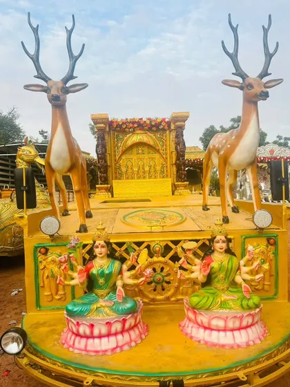 A unique procession chariot design featuring two large deer statues and seated goddesses, set against a golden backdrop.