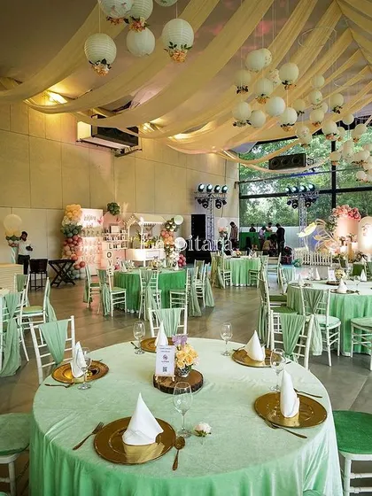 The guest seating area was designed to complement the enchanted garden theme. Tables were dressed in soft green linens, with simple centerpieces that allowed the grand stage and ceiling decor to be the main focus.