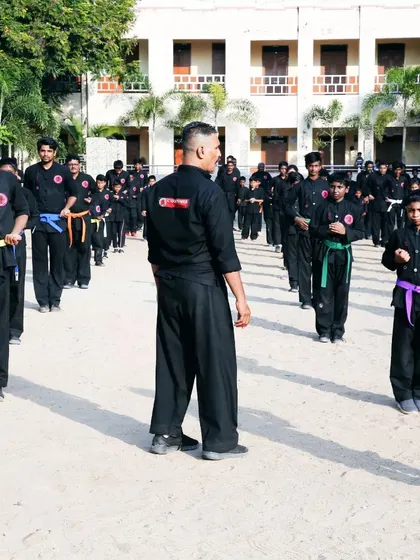 I oversee a class of students arranged in disciplined rows. My role is to observe, correct, and ensure every student is maintaining the correct form and focus during our drills.