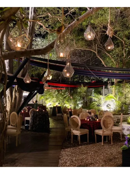 An enchanting evening setup at the Garden of Five Senses, with hanging lanterns and elegantly set tables. This showcases the magical ambiance our team helps create in collaboration with top decor vendors.