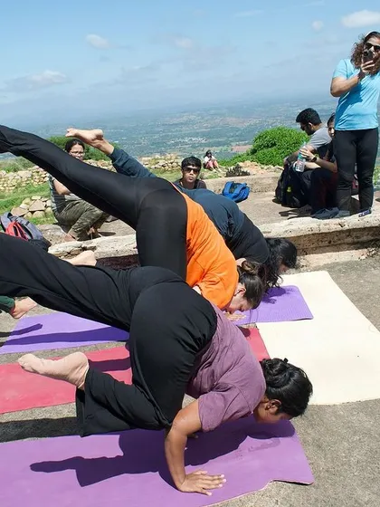 Partner yoga on a mountaintop. Students support each other in an arm balance during our yoga trek.