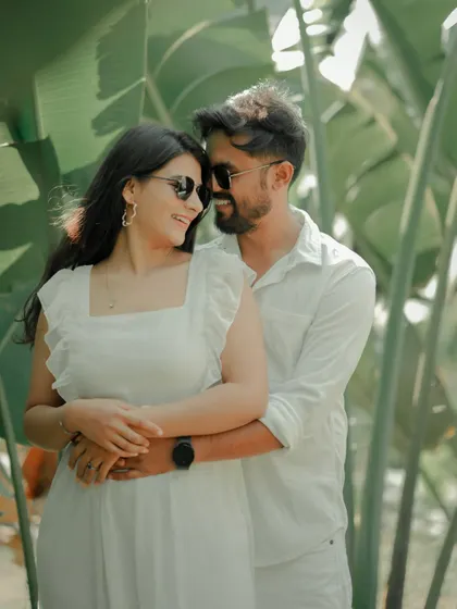 A playful and loving embrace amidst lush greenery. The couple's sunglasses and bright smiles give this candid shot a fun, relaxed vibe, perfect for a sunny day shoot in Pune.