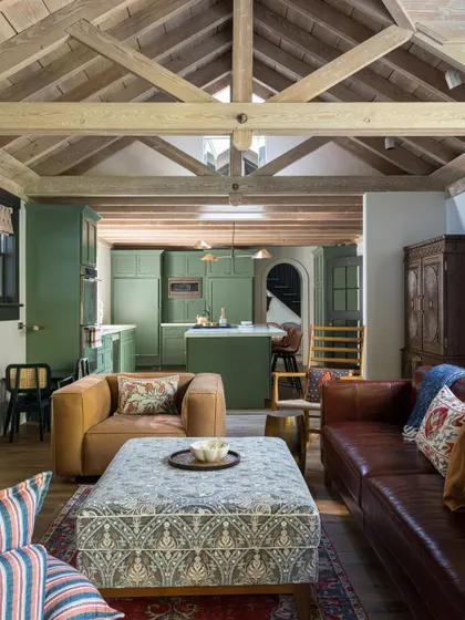 The open-plan living and kitchen area in Saratoga, a space designed for modern family life. The green of the kitchen cabinets adds a beautiful pop of color that complements the earthy tones of the living room.
