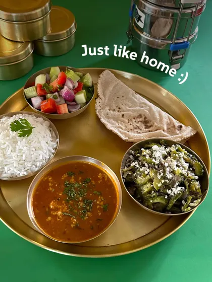 Just like home. A simple, perfectly balanced meal of paneer bhurji, a green vegetable sabzi, rice, roti, and salad, served on a traditional brass plate.