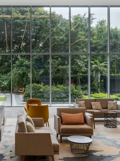 The main lobby of a corporate headquarters, designed as a welcoming and impressive entry point. The double-height space, comfortable seating, and full-length windows overlooking the landscape create a seamless connection with the outdoors.