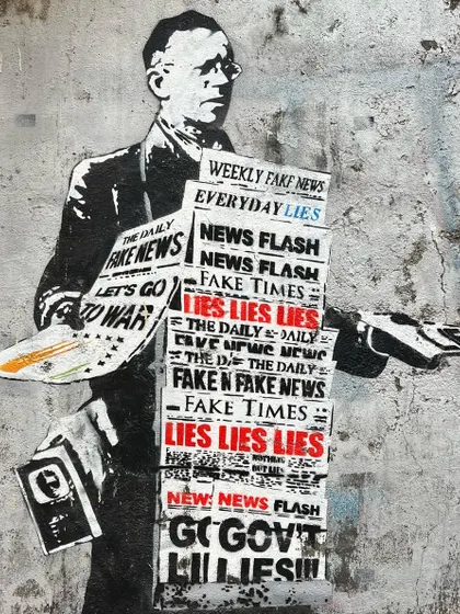 A thought-provoking piece of street art in Bandra depicting a man selling newspapers with headlines about fake news and lies.