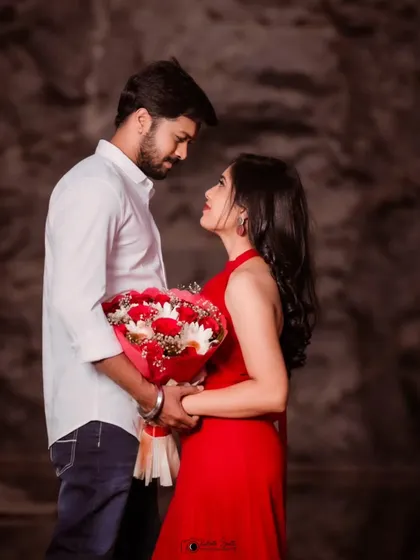 A romantic pre-wedding portrait where the couple shares an intense, loving gaze. The red dress and bouquet add a classic touch of romance to the scene.