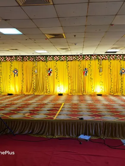 A simple Haldi stage with a full yellow drape backdrop. The stage is kept clean and open, ready for the fun and messy Haldi rituals.