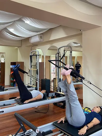 This image captures a moment of focused effort during a reformer partner session, highlighting the strength and control developed through Pilates.