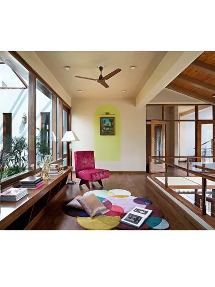 This cozy lounge area on the upper floor overlooks the central courtyard. It's a perfect example of an intermediate space, neither fully inside nor out, offering a peaceful spot to read and relax while being surrounded by light and greenery.