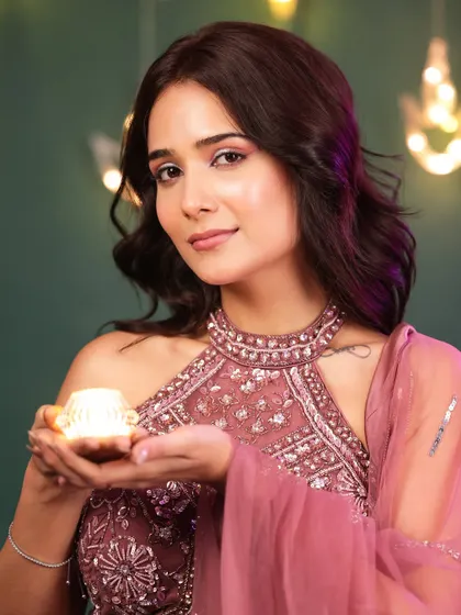 A direct and engaging portrait from the Diwali series. The model's warm smile and the soft glow of the diya create a joyful and welcoming image.