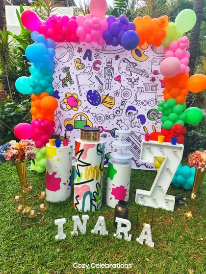 A creative and interactive art-themed party for a 7th birthday. The backdrop is a giant coloring page, and the decor includes paint splatter details and bright, vibrant colors.