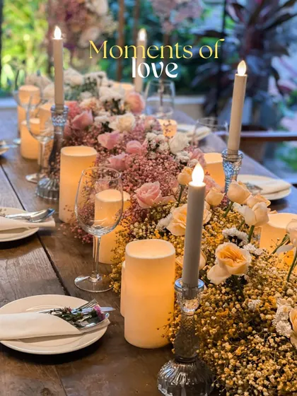 A close-up of a romantic tablescape, perfect for an anniversary dinner or an intimate proposal. The table is filled with baby's breath, roses, and an abundance of candles to create a soft, dreamy glow.