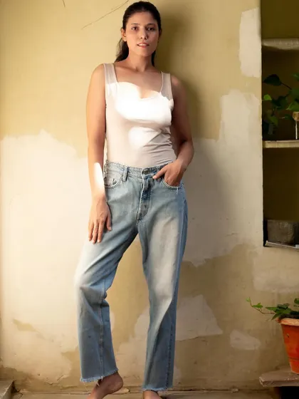 A full-length shot in a basic tank top and jeans, serving as a perfect modeling polaroid or a base for a casual styling campaign.
