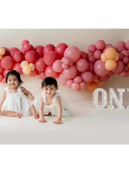 A beautiful portrait of the twin girls before the cake smash, with a large 'ONE' marquee sign.