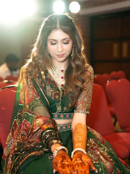 A beautiful, moody shot of the bride at her Mehendi. The soft lighting highlights her glowing skin and the rich green of her outfit.