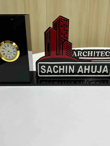 We create professional desk organizers for architects, like this one for 'Sachin Ahuja,' featuring a building design, a nameplate, a pen holder, and a clock.