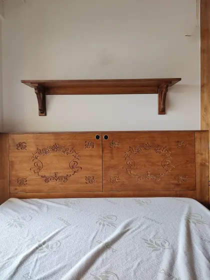 A closer look at the intricately carved headboard, which is both a beautiful design feature and a clever storage solution.