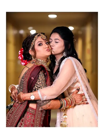A sweet moment with the bridesmaid giving the bride a kiss on the cheek. It's a beautiful capture of friendship and love on a special day.