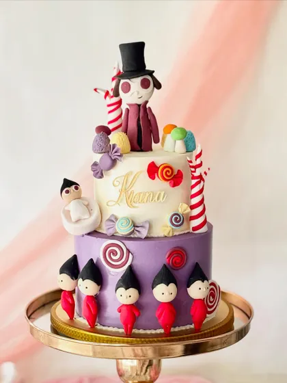 A whimsical two-tiered Willy Wonka cake. I sculpted Willy Wonka and his Oompa Loompas from fondant and surrounded them with a variety of colourful, oversized candies and lollipops.