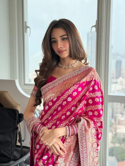 A doll-faced beauty in a stunning pink Banarasi saree for her engagement. The makeup is soft and pretty, with a focus on enhancing her youthful features.