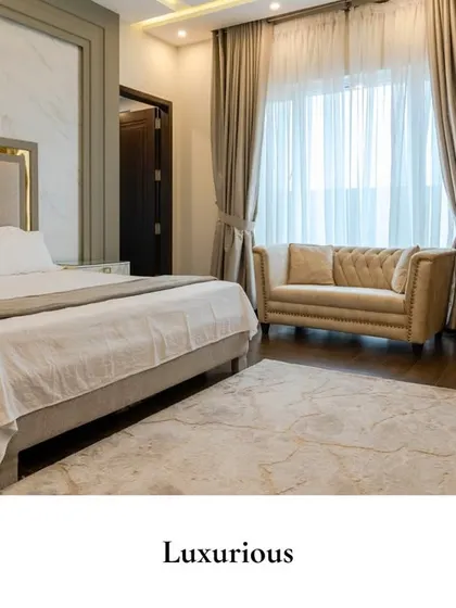 This bedroom pairs quiet opulence with modern sensibilities. A marble-finish wall panel acts as a striking backdrop, softened by the upholstered bed and a classic tufted sofa, creating a space of effortless grace.