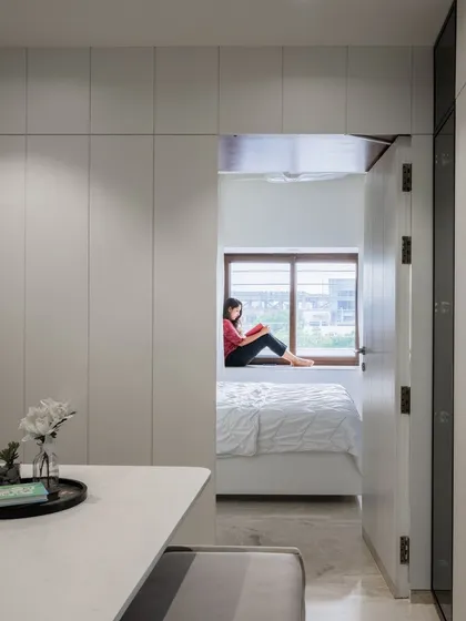 A view from the dining area offers a sneak peek into the master bedroom, showing how we used concealed doors within the wall paneling to create a hidden, private sanctuary.