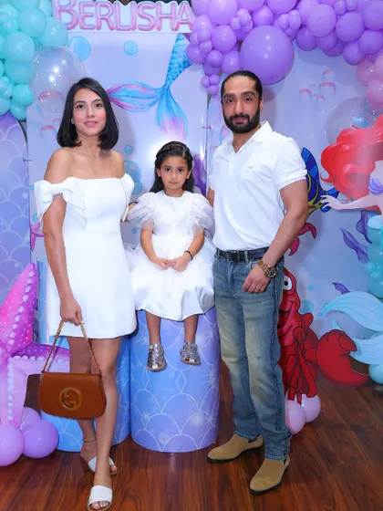 A stylish family portrait at our mermaid-themed party. The "under the sea" backdrop with its shades of purple and teal creates a beautiful setting for photos.