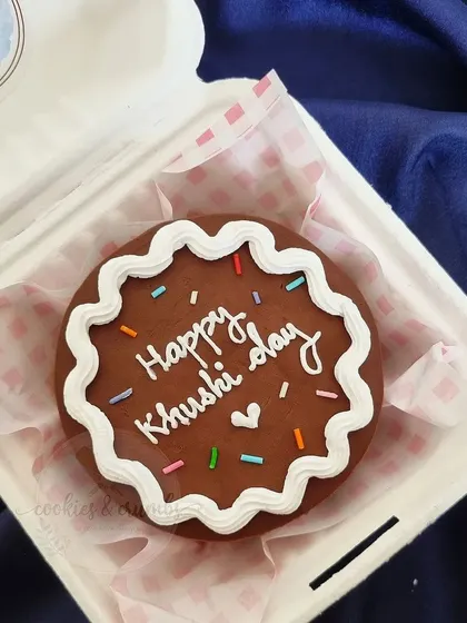 A chocolate bento cake that looks like a giant cookie. The piped border and colorful sprinkles give it a classic, happy birthday feel.