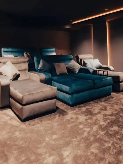 This room features a mix of chaise lounges and sofas, all upholstered in luxurious fabrics. The textured carpet and soft lighting add to the room's comfort.