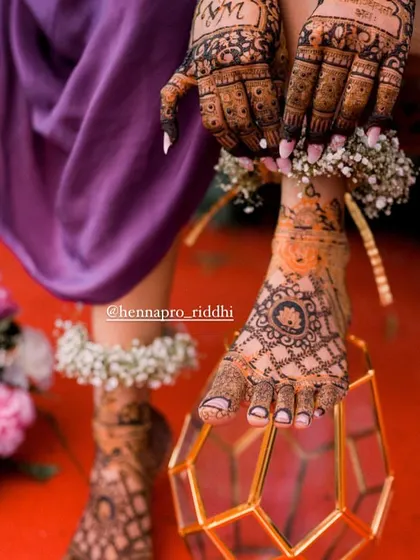 Bridal photoshoots are the perfect time to show off every detail. This creative shot highlights the beautiful foot henna, adorned with floral anklets, for a truly magical picture.