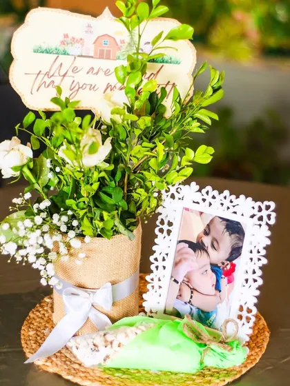 A beautiful, rustic table centerpiece. The arrangement includes fresh flowers in a burlap-wrapped vase, a custom sign, and a framed photo of the birthday boys.