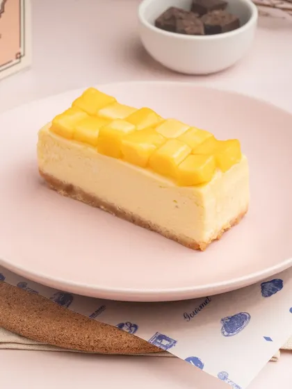 A beautiful slice of my Mango Cheesecake, topped with perfectly diced fresh mango. It's a creamy, fruity dessert that captures the essence of summer.