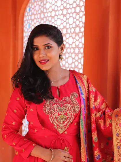 A vibrant look for a pre-wedding photoshoot. The red outfit and bold lip stand out beautifully against the colorful backdrop.