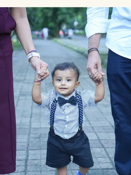 A baby's first steps are a memory a family holds forever. Here, little Krishiv is safely guided by his parents' hands, a simple, powerful image of love and support that defines family photography.