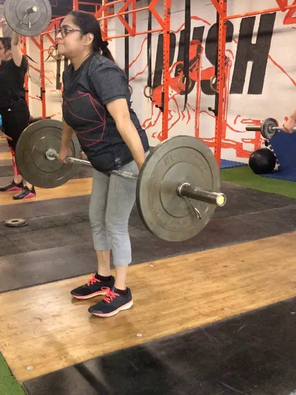 A female lifter begins a snatch from the hang position. This drill is a staple in my programs for improving technique and power development for all my athletes.