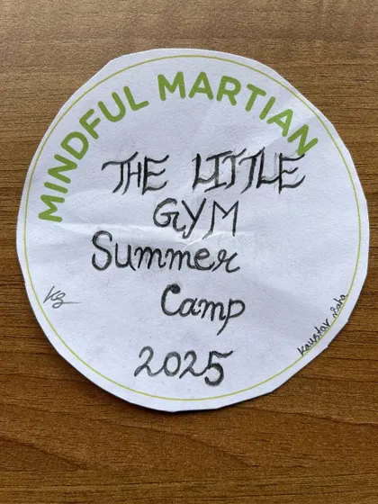 A proud camper shows off their "Mindful Martian" badge from our 2025 summer camp. These creative activities help solidify what they've learned in a personal and memorable way.