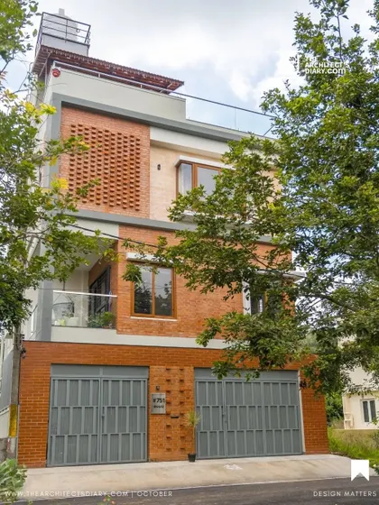 The completed Vivek Residence, featuring an earthy facade of exposed brick and simple grey gates. This design was recognized for its ability to bring sunshine into a compact plot.