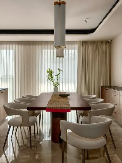 The dining area of the Parishram residence, featuring a long wooden table and custom sideboards that provide ample storage while maintaining a sleek profile.
