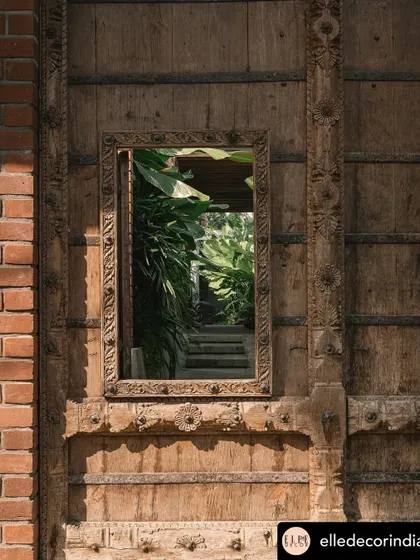 A reclaimed wooden door features a mirror that reflects the garden, cleverly bringing the landscape inside. This detail is part of a larger strategy to ensure every corner of the home has a connection to the green spaces I designed.