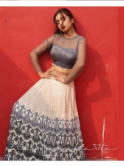 A chic and modern lehenga in grey and cream georgette. The skirt features intricate threadwork, paired with a stylish tulle crop top with shell detailing for a beach wedding or cocktail party.