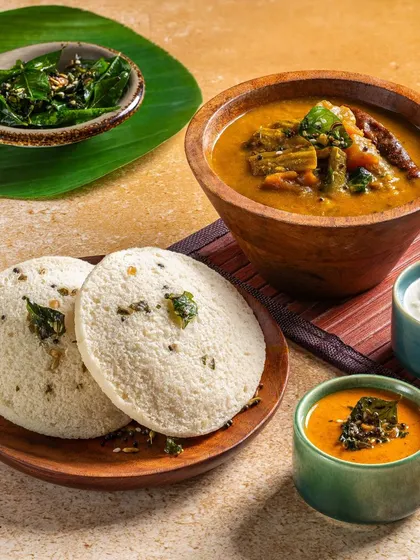 A comforting plate of idli and sambar, styled with a banana leaf and traditional wooden bowls for an authentic South Indian feel.